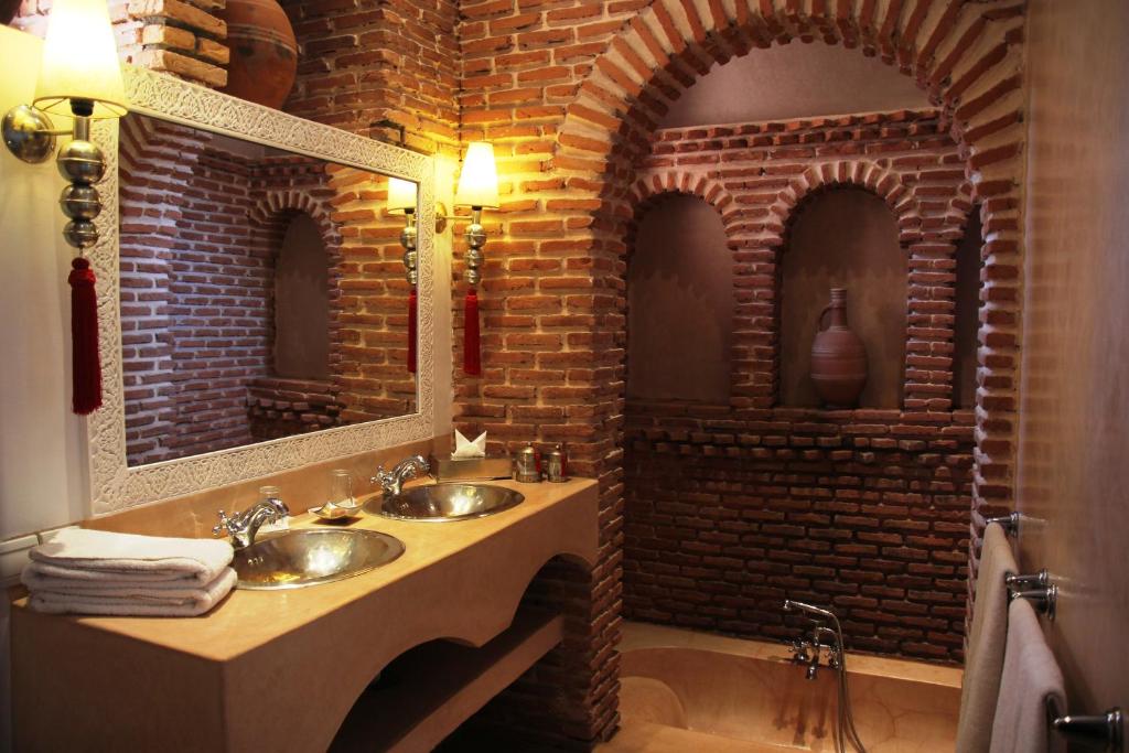 La salle de bains est pourvue de 2 lavabos et d'un mur en briques. dans l'établissement Riad Clémentine, à Marrakech