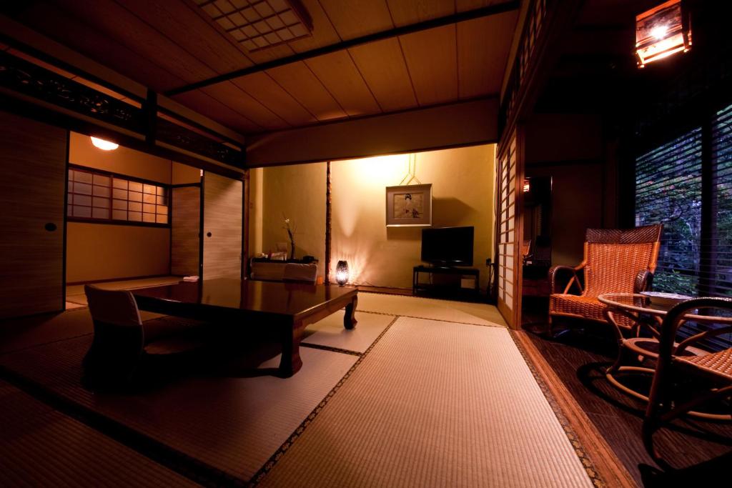un salon avec une table, des chaises et une télévision dans l'établissement Ryokan Sennari (13 years or older), à Beppu