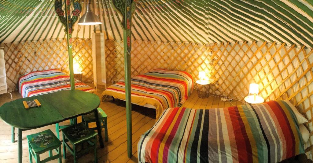 - une chambre avec 2 lits et une table dans une yourte dans l'établissement Yourtes Mongoles Gavarnie, à Gèdre