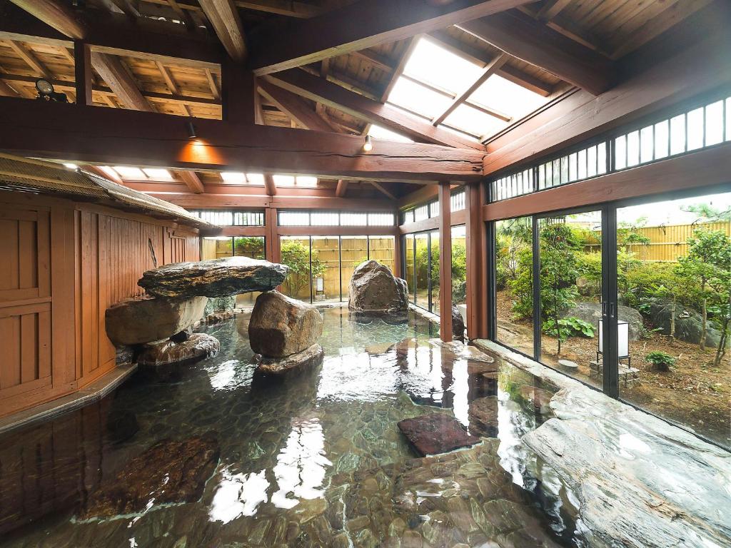 Cette chambre dispose d'une piscine d'eau avec des rochers. dans l'établissement Yuraku Hotel, à Awara