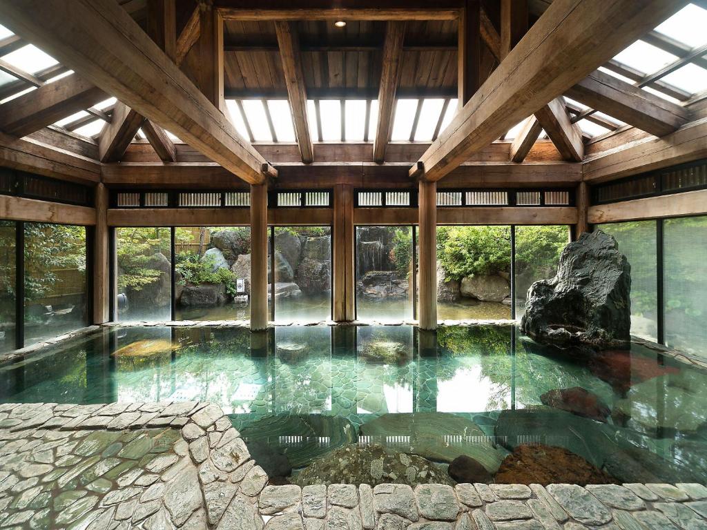 - une grande piscine d'eau dans un bâtiment avec un rocher dans l'établissement Yuraku Hotel, à Awara