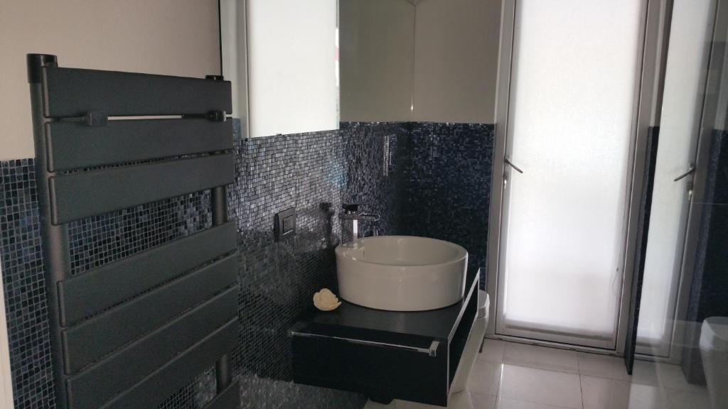 La salle de bains est pourvue d'un lavabo sur un mur en carrelage noir. dans l'établissement Villa Ines con piscina sud Sardegna, à Capoterra