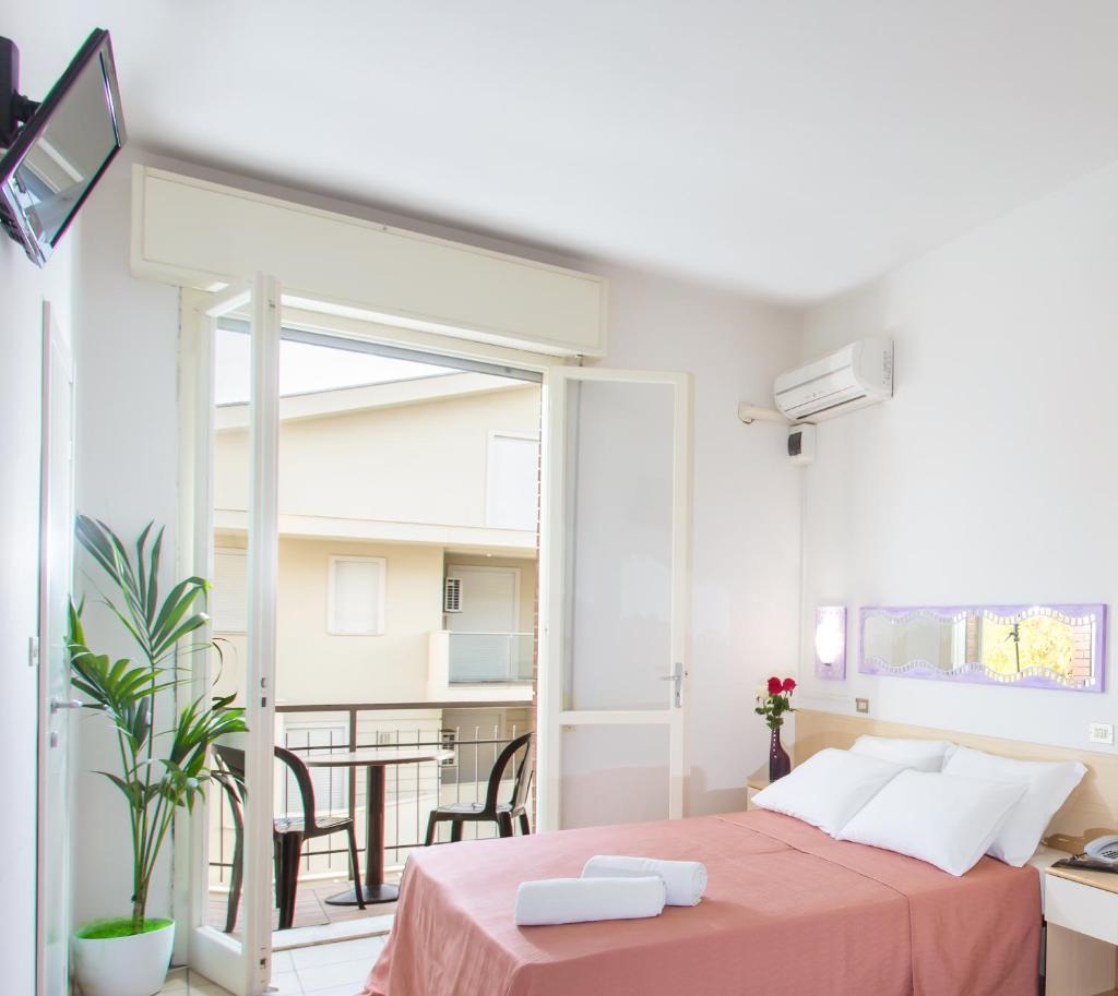 une chambre avec un lit et un balcon avec une table dans l'établissement HOTEL OLIVER, à Cervia