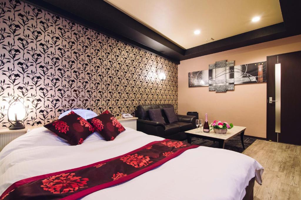 une chambre d'hôtel avec un lit et une chaise dans l'établissement Tinkerbell (Adult Only), à Takamatsu