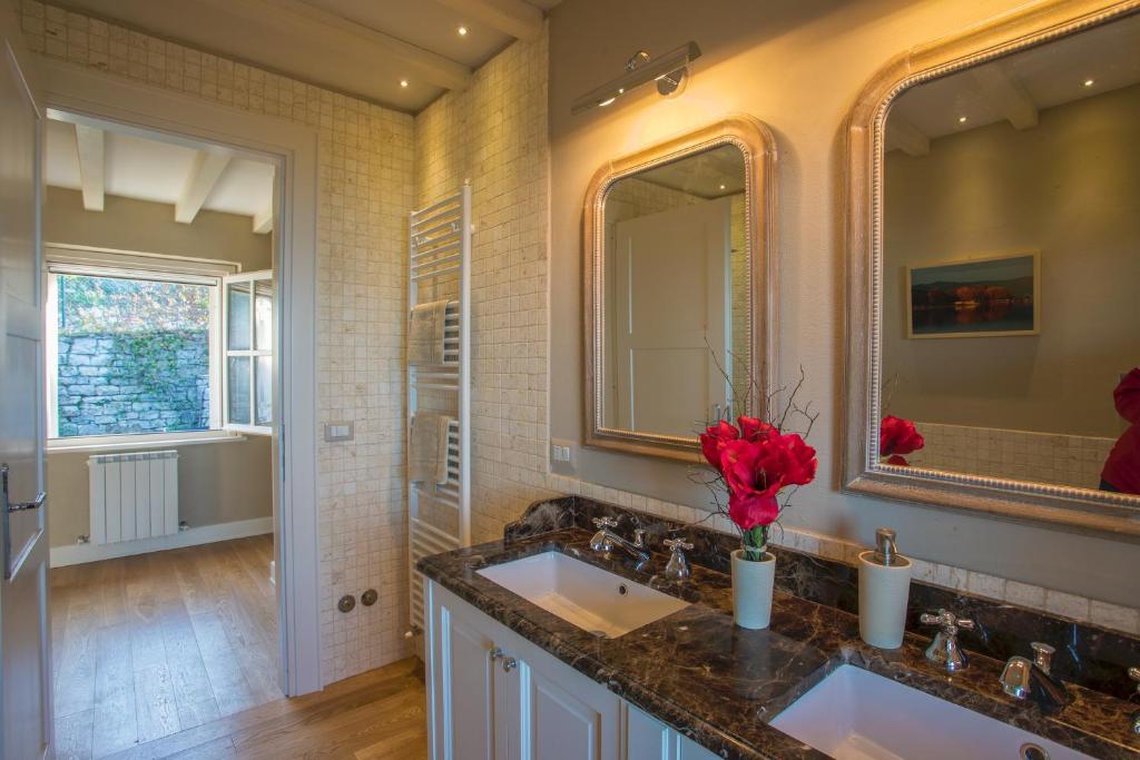 une salle de bain avec deux lavabos et un miroir dans l'établissement Bianca la Luna amazing villa lakeside view, à Magione