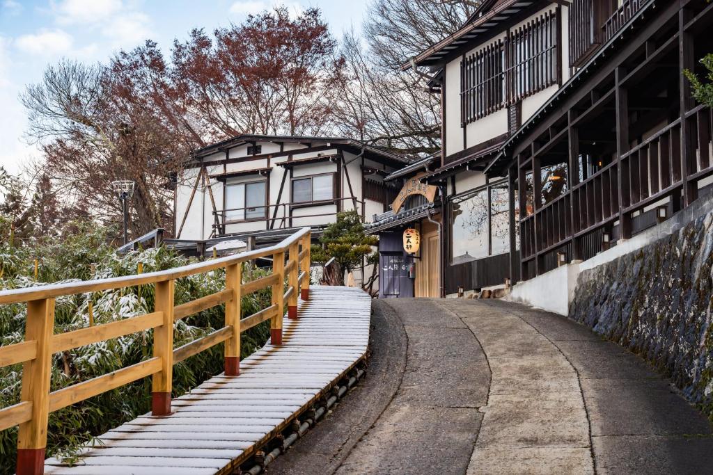 une passerelle devant un bâtiment avec une clôture dans l'établissement Hidatakayama Futarishizuka Hakuun, à Takayama