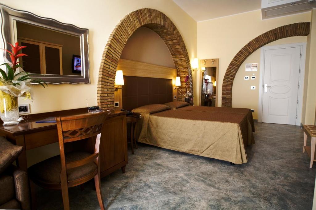 une chambre d'hôtel avec un lit et un miroir dans l'établissement Hotel Villa Tirreno, à Tarquinia