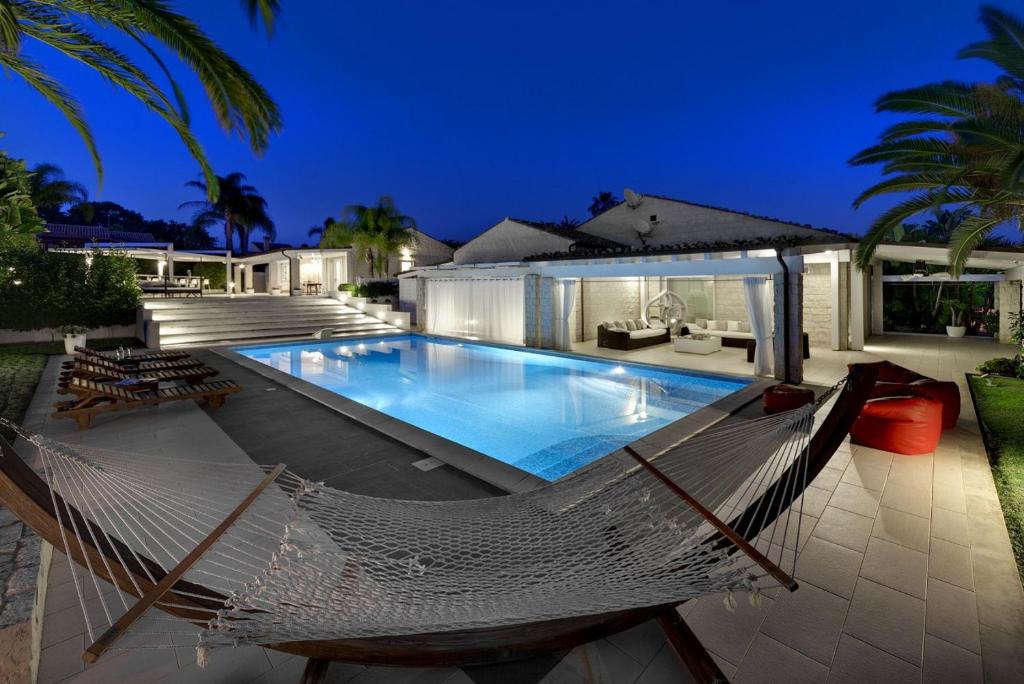 une piscine avec un hamac devant une maison dans l'établissement Villa Pietrabianca, à Scicli