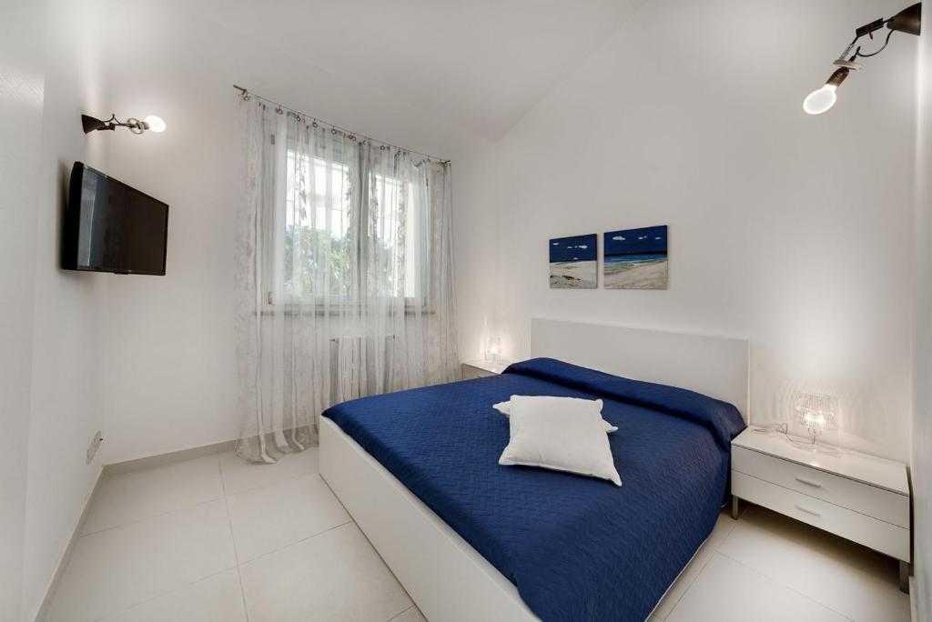 - une chambre blanche avec un lit bleu et une fenêtre dans l'établissement Villa Pietrabianca, à Scicli
