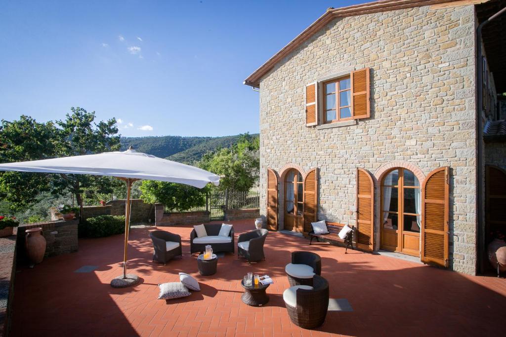 une terrasse avec des chaises et un parasol en face d'un bâtiment dans l'établissement Corte della Luna, à Cortone