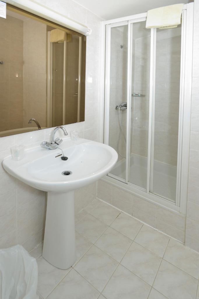 une salle de bain blanche avec un lavabo et une douche dans l'établissement Hotel Le Cairn, à Les Deux Alpes