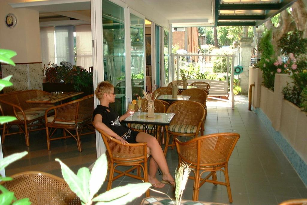 un jeune garçon assis à une table dans un restaurant dans l'établissement Hotel Kadett, à Rimini