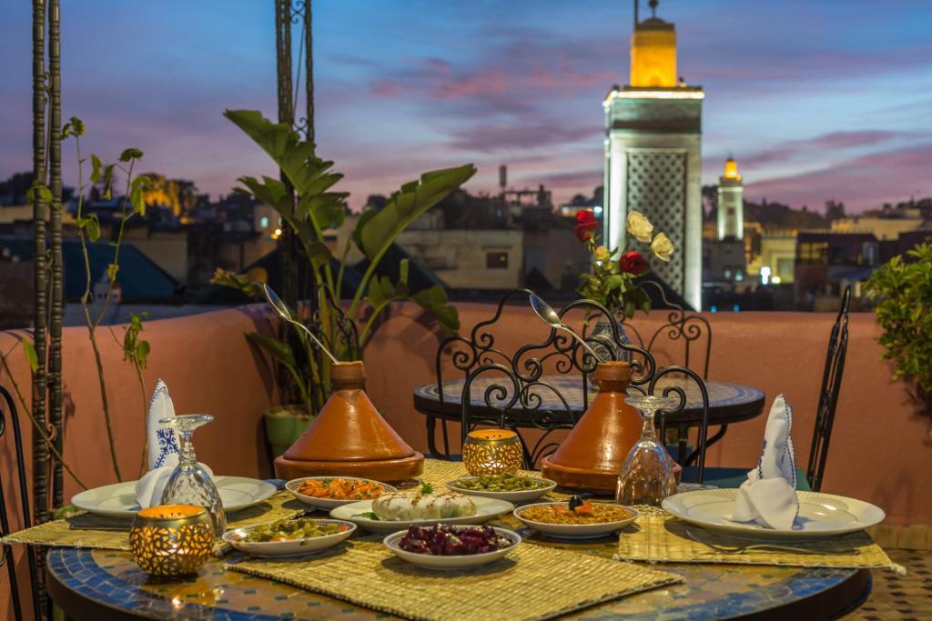 une table avec des assiettes de nourriture et des vases sur un balcon dans l'établissement Riad Hala, à Fès