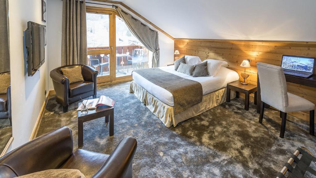 une chambre d'hôtel avec un lit, un bureau et une chaise dans l'établissement Hotel La Chaudanne, à Méribel