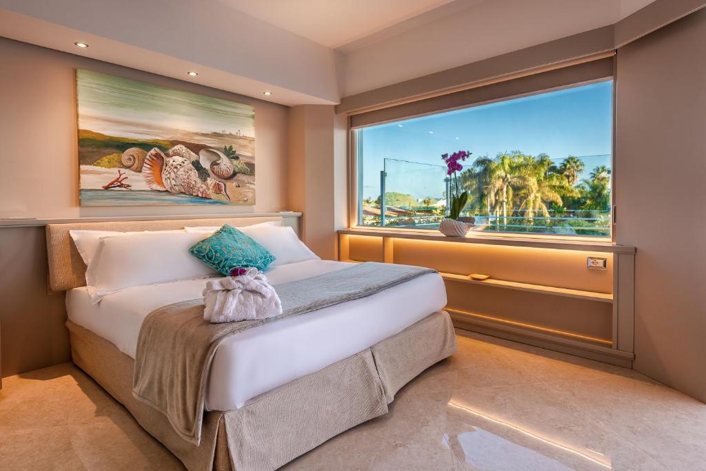 une chambre avec un lit et une grande fenêtre dans l'établissement Acacia Palace, à Marina di Ragusa