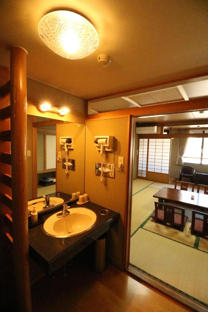 une salle de bain avec un lavabo et un grand miroir dans l'établissement Wakamizusou, à Fujikawaguchiko