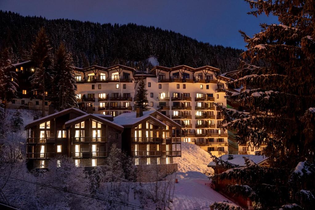 un grand bâtiment dans la neige la nuit dans l'établissement Yellowstone Lodge by Alpine Resorts, à La Tania