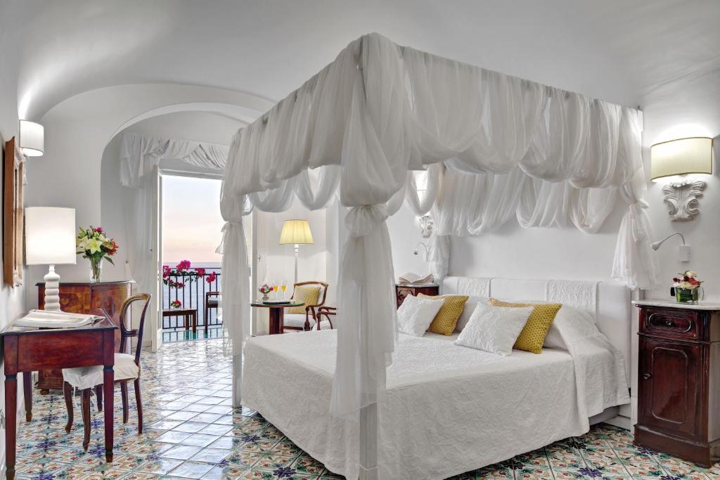 une chambre avec un lit blanc à baldaquin dans l'établissement Hotel Santa Caterina, à Amalfi