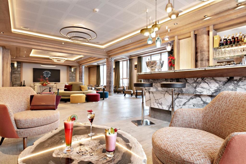 un hall avec des canapés et un bar avec des boissons sur une table dans l'établissement MGM Hôtels & Résidences - Résidence Anitea, à Valmorel