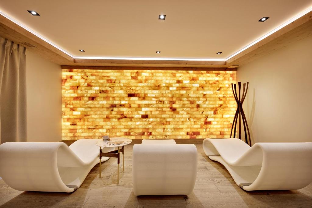 - un hall avec des chaises blanches et un mur en briques dans l'établissement MGM Hôtels & Résidences - Résidence Anitea, à Valmorel