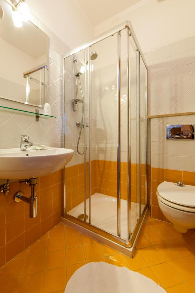 une salle de bain avec douche, lavabo et toilettes dans l'établissement Hotel President, à Bibione