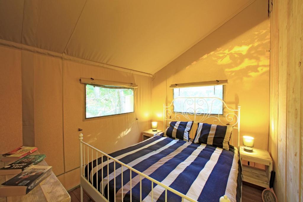 une chambre avec un lit à rayures bleues et blanches dans l'établissement Camping Le Pech Charmant, à Les Eyzies-de-Tayac 37 autres photos