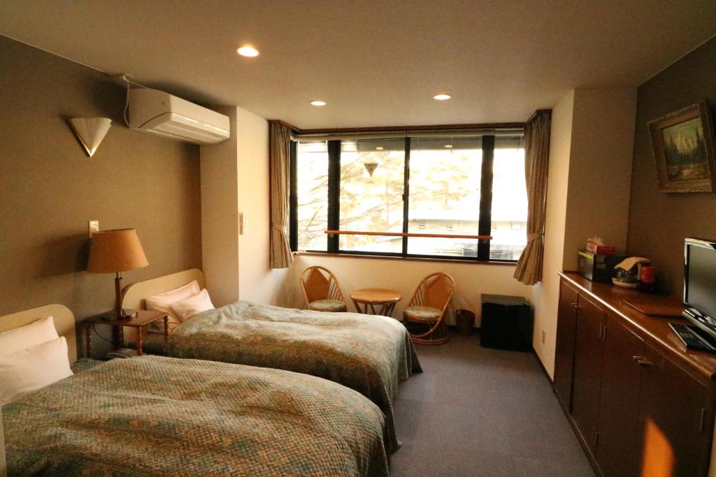 une chambre d'hôtel avec deux lits et une fenêtre dans l'établissement Wakamizusou, à Fujikawaguchiko