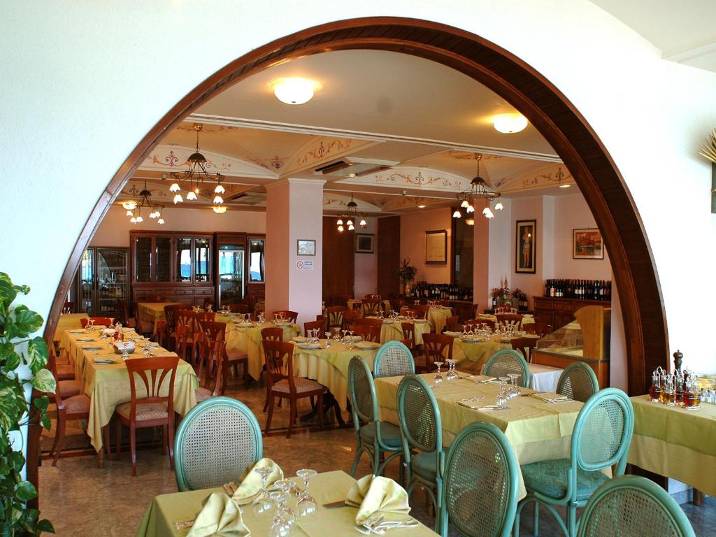 un restaurant avec des tables, des chaises et un grand miroir dans l'établissement Hotel Il Mulino, à Capo dʼOrlando