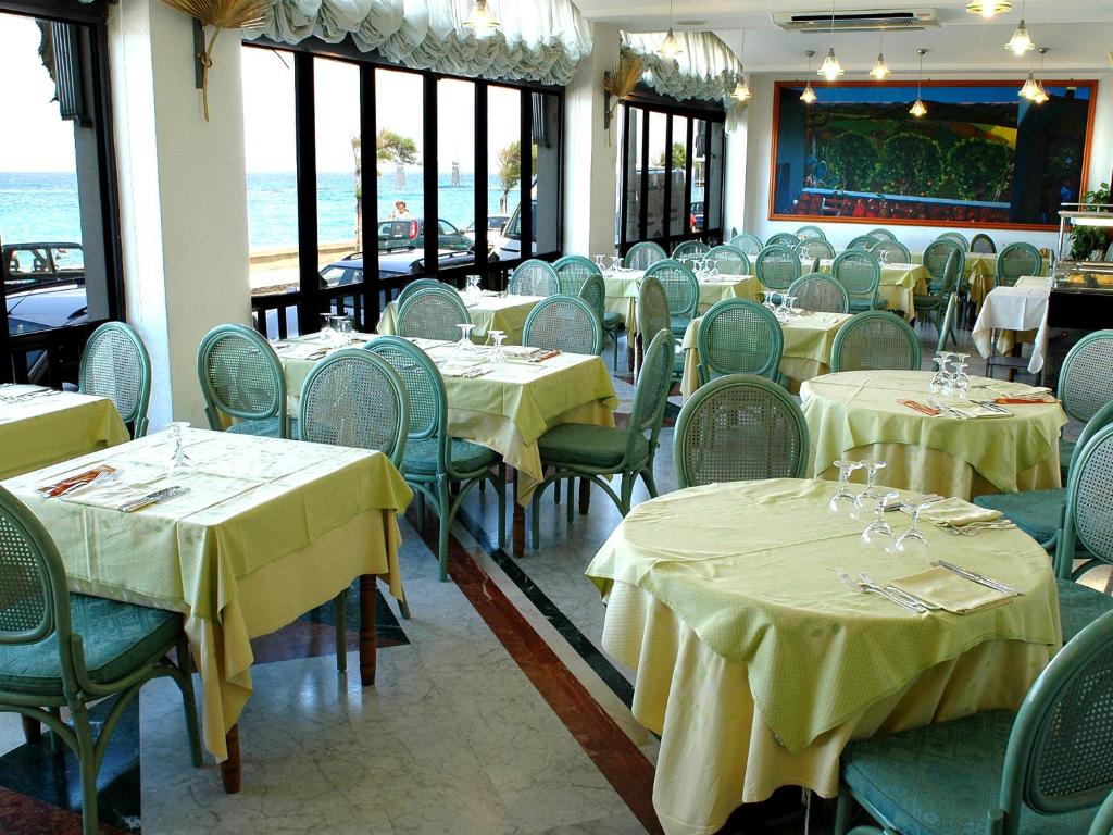 une salle à manger avec des tables, des chaises et un tissu de table jaune dans l'établissement Hotel Il Mulino, à Capo dʼOrlando 41 autres photos