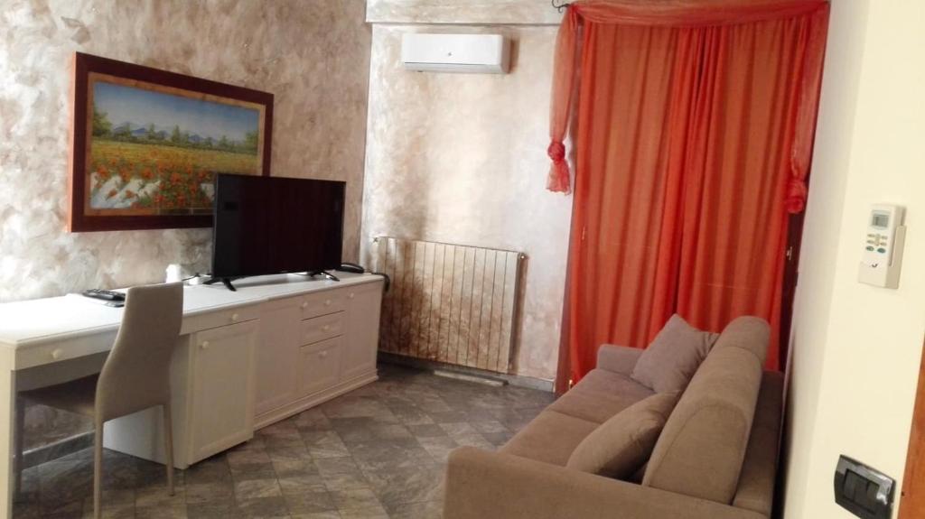 un salon avec un canapé et un bureau avec une télévision dans l'établissement Hotel Esperia, à Piombino