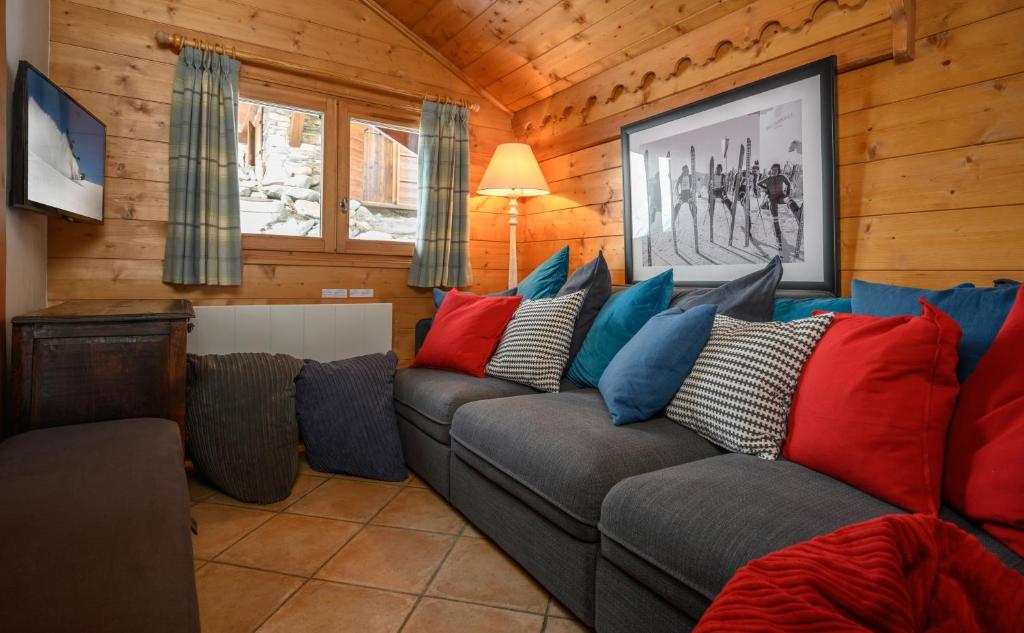 - un salon avec un canapé gris et des oreillers colorés dans l'établissement Chalet Ananas, Hameau des Marmottes, aux Menuires