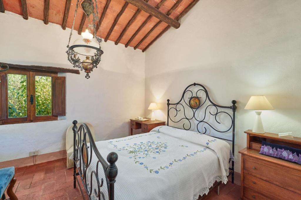 une chambre avec un lit et un lustre dans l'établissement Casale Sandonatino by VacaVilla, à Castellina in Chianti