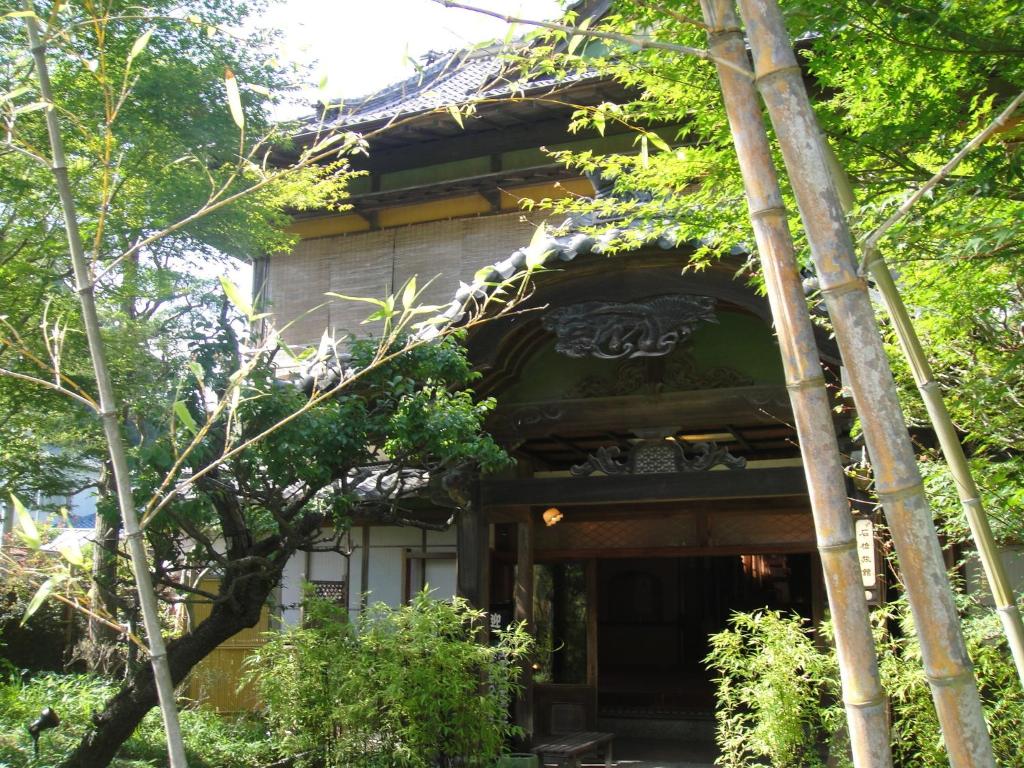 un bâtiment avec des arbres devant dans l'établissement Kurhaus Ishibashi Ryokan, à Shimoda
