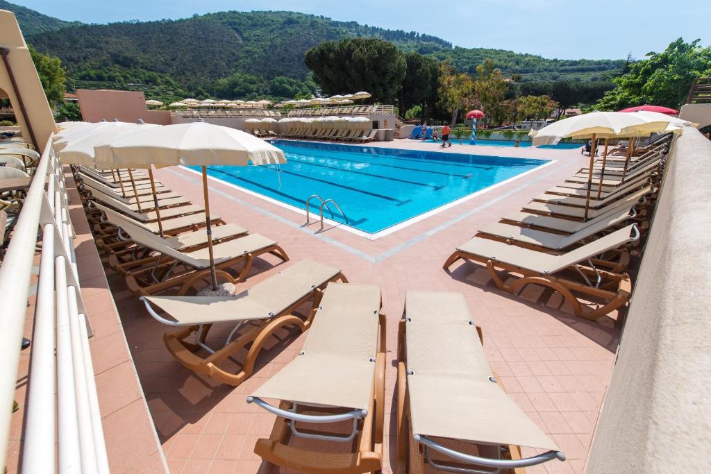 une piscine avec des chaises longues et une piscine dans l'établissement Il Villaggio Di Giuele, à Finale Ligure