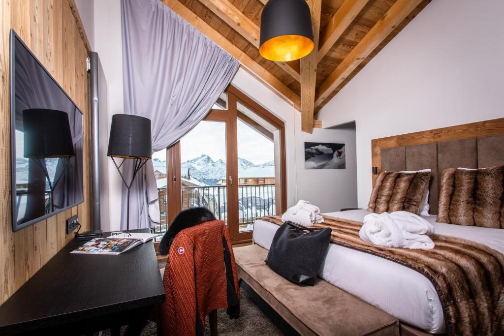 une chambre avec un lit, un bureau et une fenêtre dans l'établissement Hôtel Daria-I Nor by Les Etincelles, à L'Alpe-d'Huez