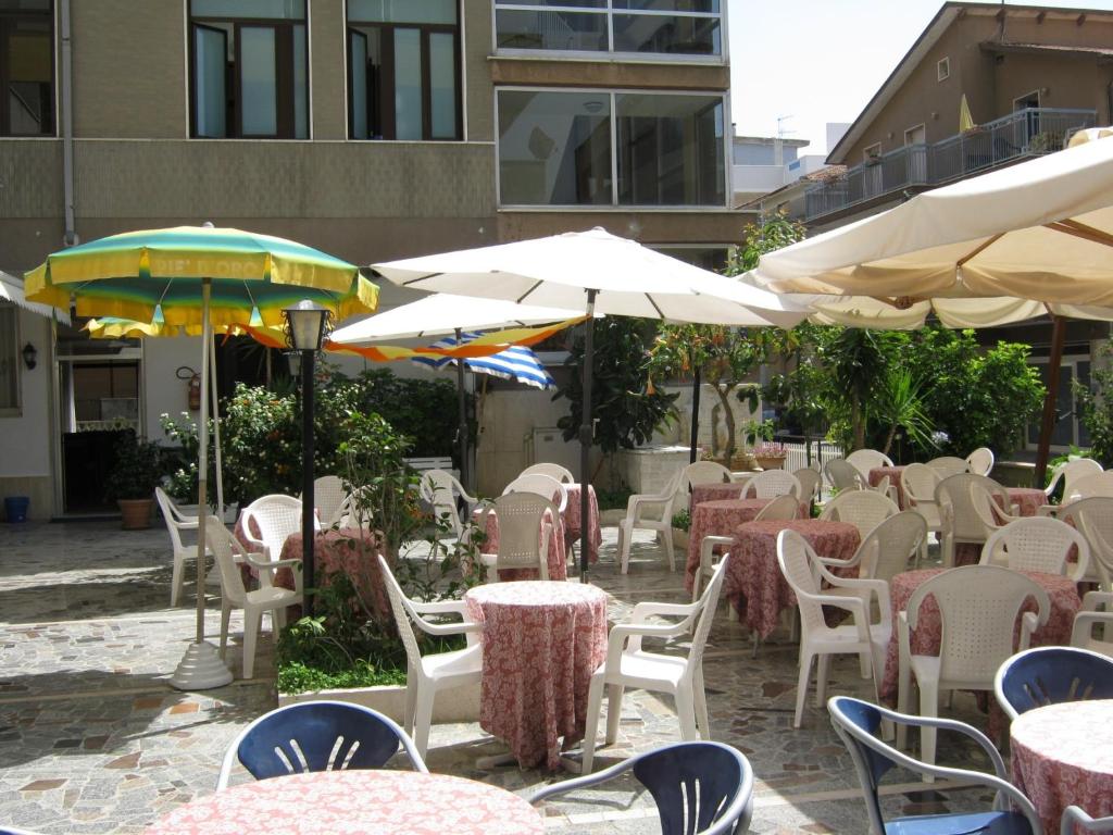 un café en plein air avec des tables, des chaises et des parasols dans l'établissement Hotel Blurelda, à Silvi Marina