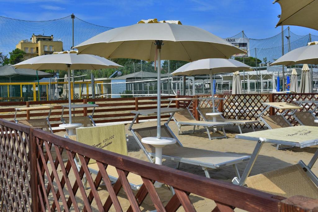 un groupe de tables et de chaises avec parasols dans l'établissement Hotel Manila, à Cervia