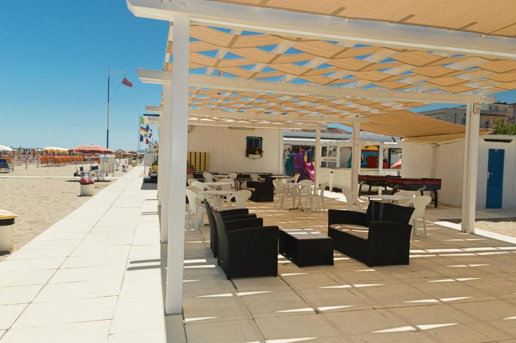 un patio avec chaises et tables sur la plage dans l'établissement Hotel Karin, à Rimini