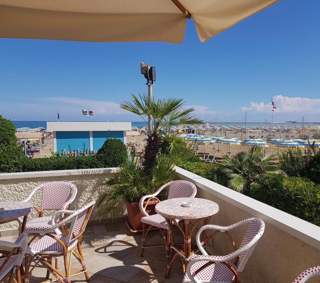 d'un balcon avec des tables et des chaises et une vue sur la plage. dans l'établissement Hotel Driade sul mare, à Rimini