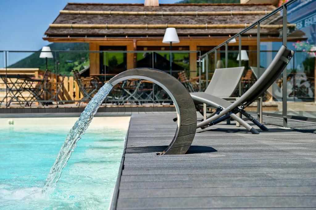 une piscine avec une fontaine à eau dans l'établissement Hôtel-Chalet Les Ecureuils Restaurant, Piscine, Jardin Garage, au Grand-Bornand