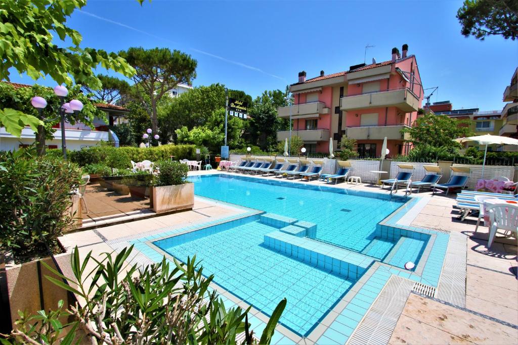 une grande piscine avec des chaises et un bâtiment dans l'établissement Hotel De Amicis, à Riccione