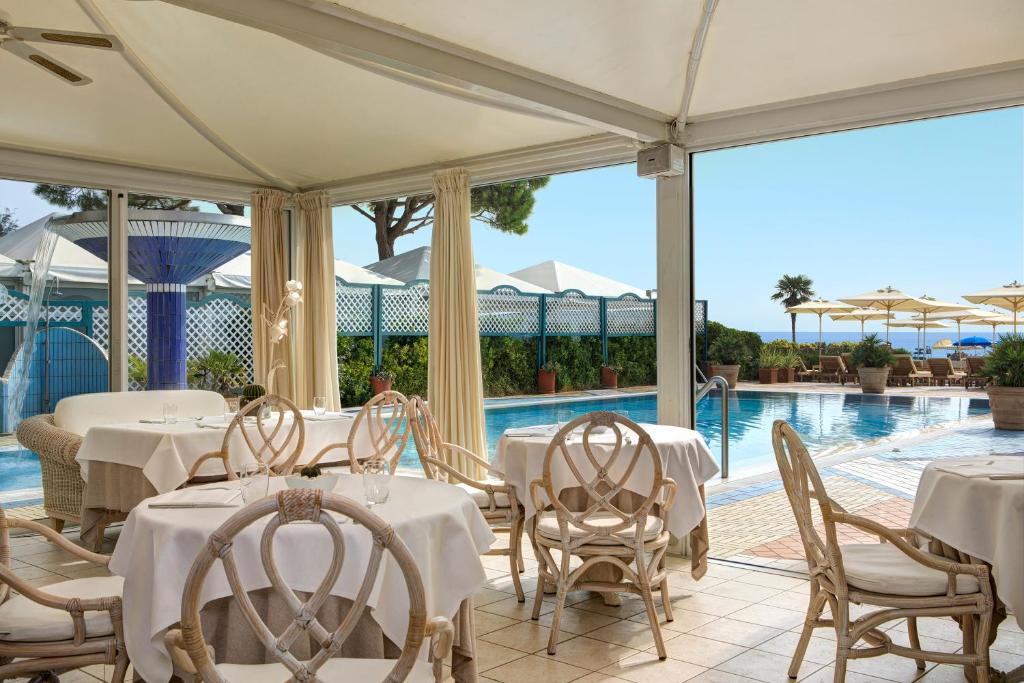 un restaurant avec des tables et des chaises blanches et une piscine dans l'établissement Park Hotel Brasilia, à Lido di Jesolo