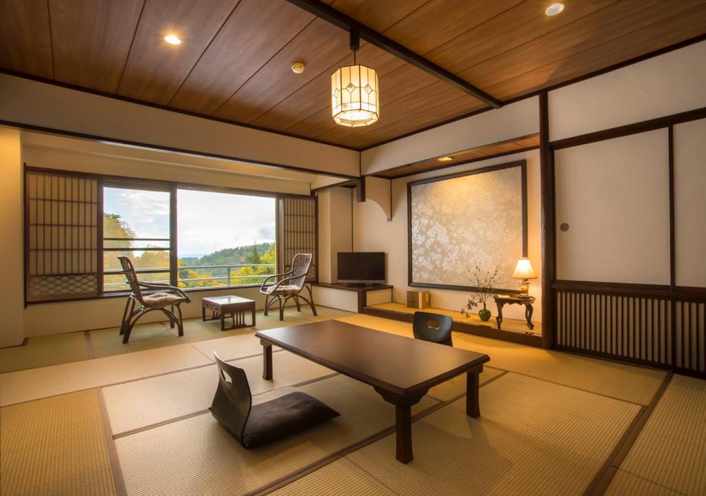 un salon avec une table, des chaises et une télévision dans l'établissement Tateshina Shinyu Onsen, à Chino