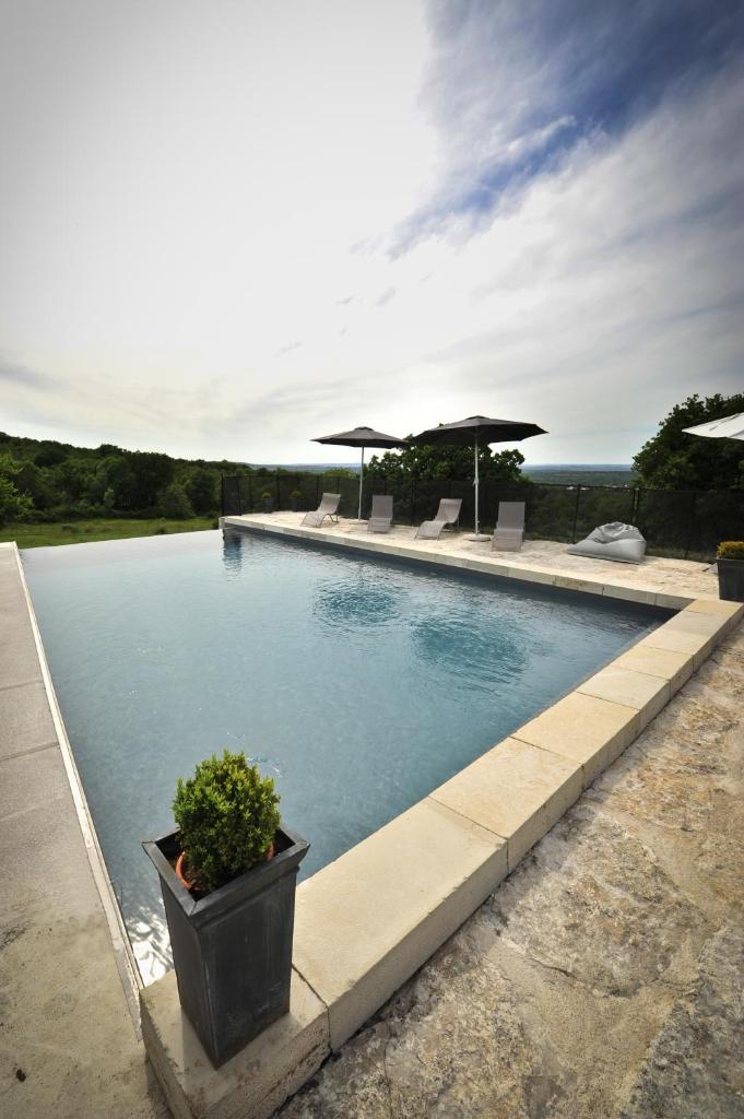 - une piscine avec une plante en pot et des parasols dans l'établissement Gîte 8 pers du Château de Cantecor, à Alvignac 16 autres photos