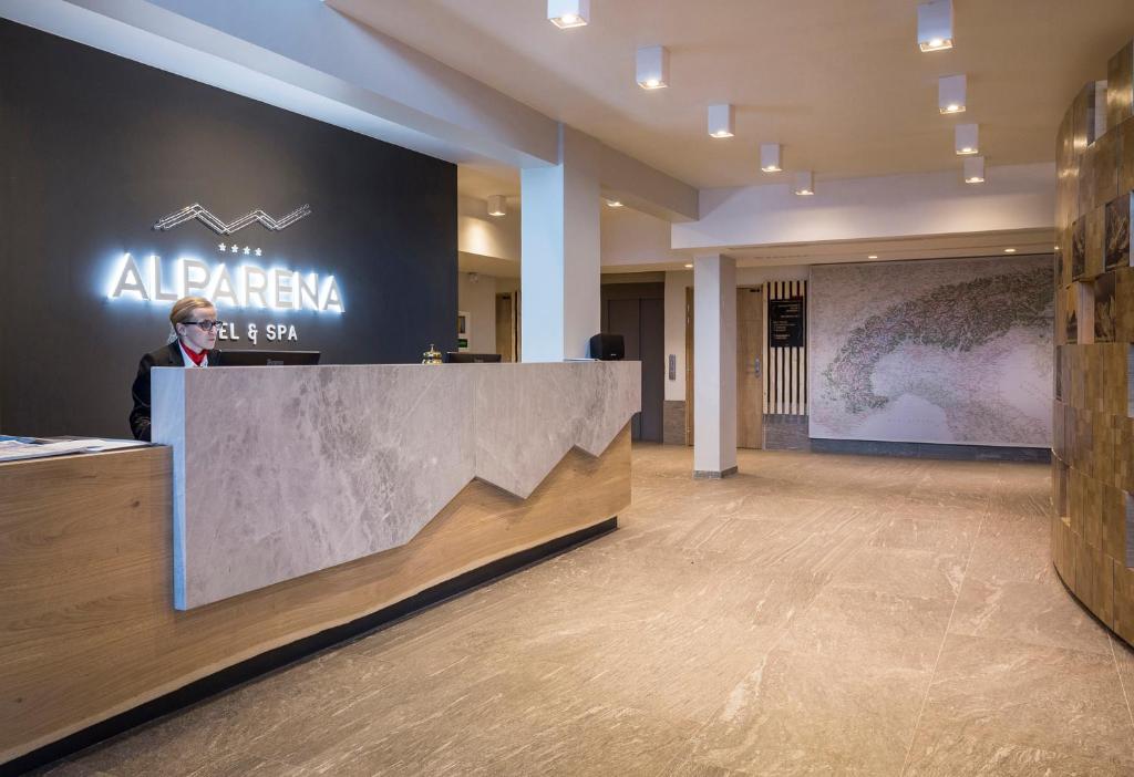 un homme debout à un comptoir dans un hall dans l'établissement Hôtel Alparena & Spa - 4 étoiles, à La Rosière 37 autres photos