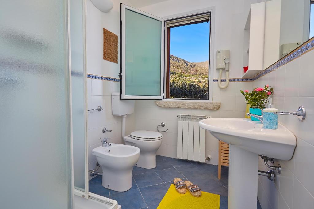 une salle de bain avec un lavabo et des toilettes et une fenêtre dans l'établissement Villa Gaia - Scopello-Villas, à Scopello
