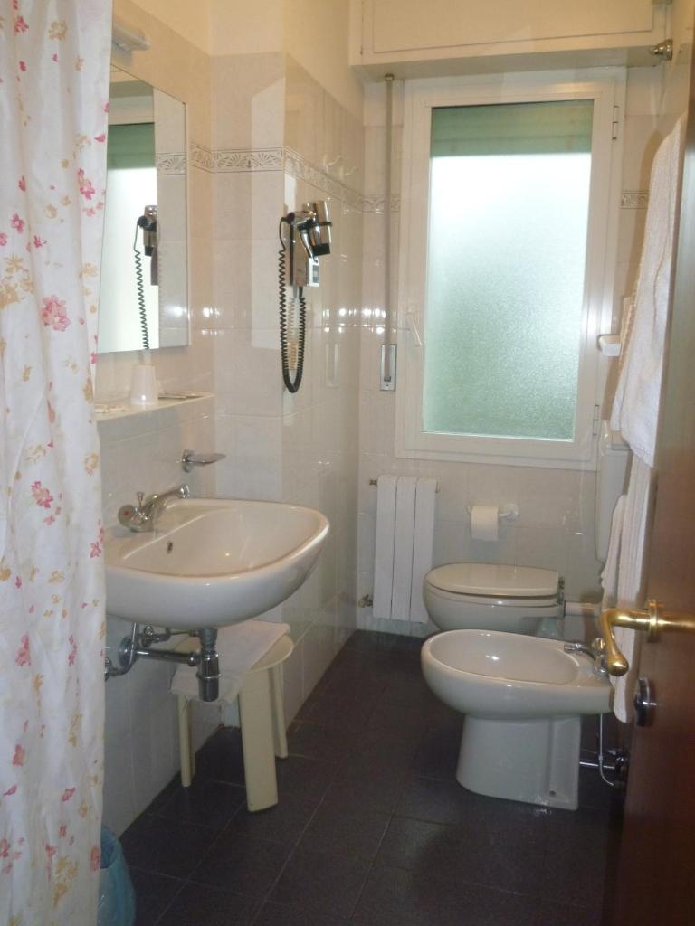 une salle de bain avec un lavabo et des toilettes et une fenêtre dans l'établissement Hotel Capri, à Diano Marina