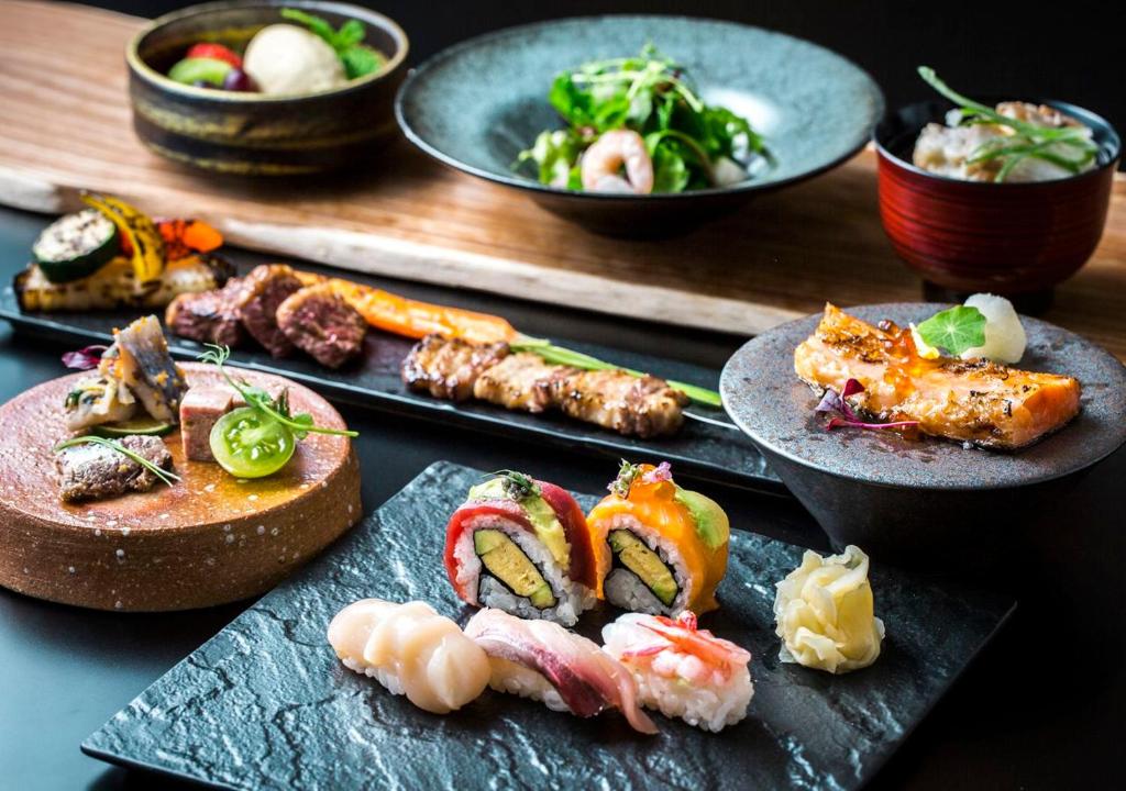 une table recouverte de plateaux de sushis et d'autres aliments dans l'établissement Hotel Sonia Otaru, à Otaru