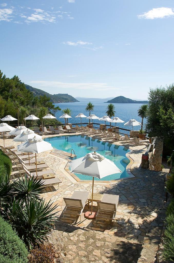 une piscine avec chaises et parasols et l'océan dans l'établissement Il Pellicano, à Porto Ercole