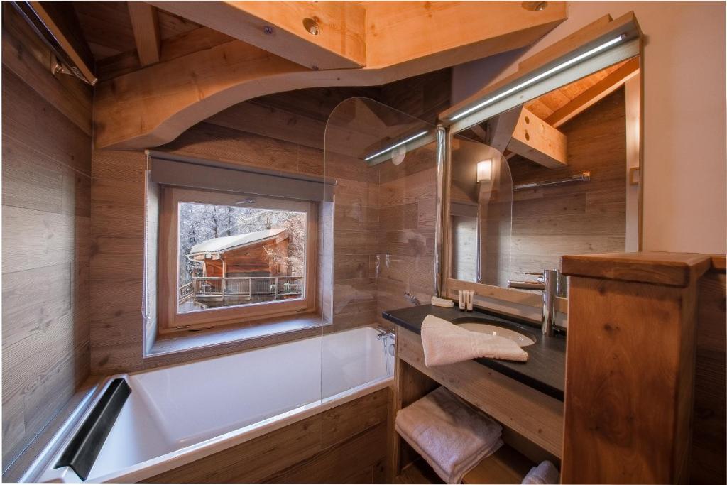 une salle de bain avec une baignoire, un lavabo et une fenêtre dans l'établissement Hotel & Restaurant Les Escondus, à Vars